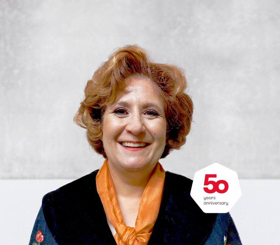 Portret van Patrizia Christen, Collection Specialist, EOS Zwitserland, die voor een heldere achtergrond staat.