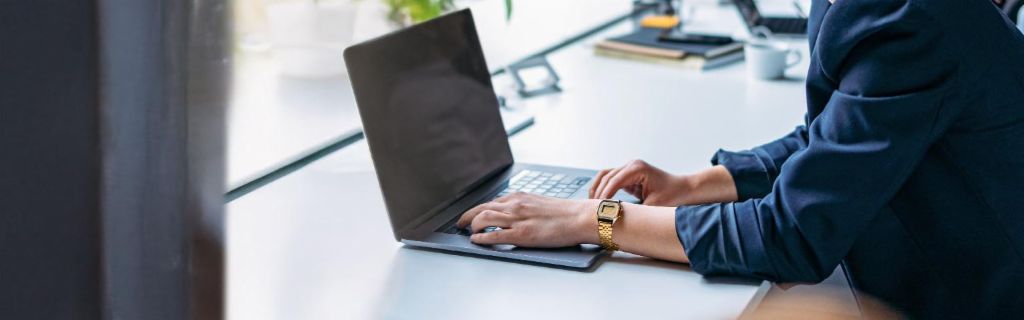 Jonge vrouw werkt op een laptop in een modern kantoor.