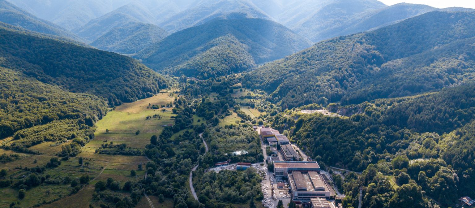 Gestion des créances : L'image montre une vue aérienne de l'usine de marbre de Berkovitsa, entourée de nombreux arbres dans une vallée. Grâce à l'engagement d'EOS, l'entreprise traditionnelle a été préservée.