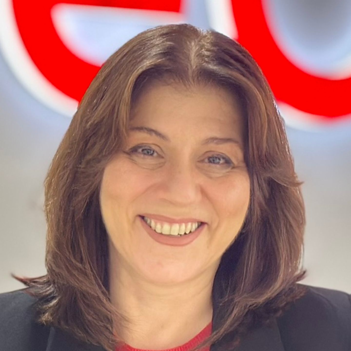 Belén Barreiro, Contact Center Agent bij EOS in Spanje, leunt tegen een toonbank in een zwart jasje voor een fel EOS-logo.