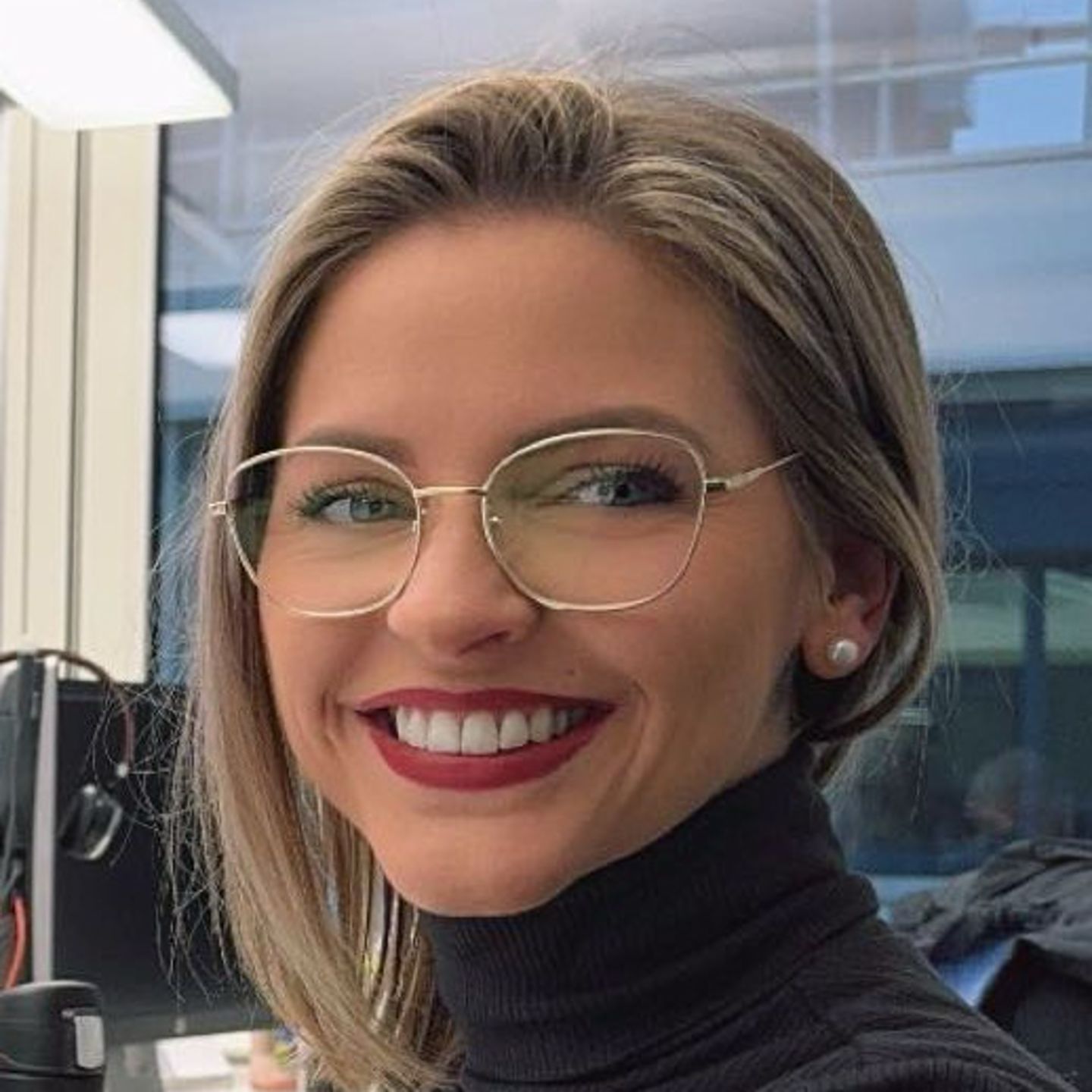 Genny Bollinger, Debt Restructuring Specialist bij EOS in Zwitserland, zit aan haar bureau in een grijze coltrui en lacht naar de camera.