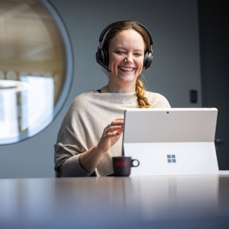 Een EOS-medewerker draagt een headset en is te zien terwijl hij glimlachend in gesprek is met een digitale tegenhanger.