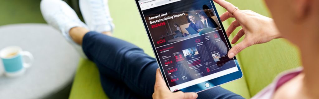 Persoon op groene bank die het EOS Jaarverslag en Duurzaamheidsverslag 2024/25 bekijkt op een tablet