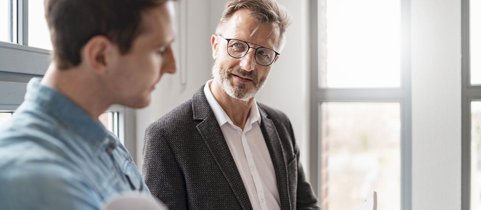 Twee mannen in een kantoor bespreken de resultaten van de EOS Group's European Payment Practices 2025 studie over digitalisering in debiteurenbeheer.