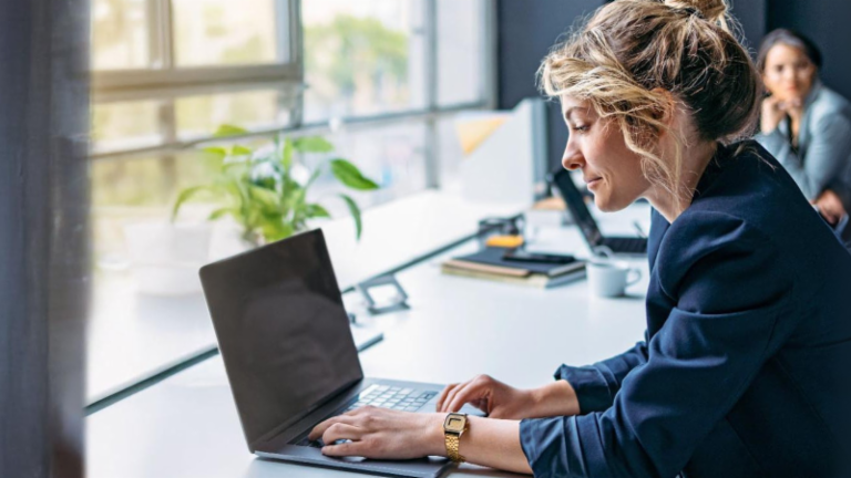 Jonge vrouw werkt op een laptop in een modern kantoor.