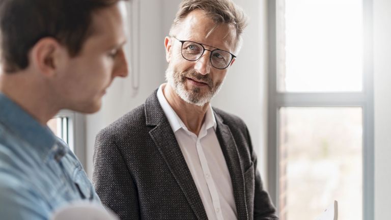 Twee mannen in een kantoor bespreken de resultaten van de EOS Group's European Payment Practices 2025 studie over digitalisering in debiteurenbeheer.