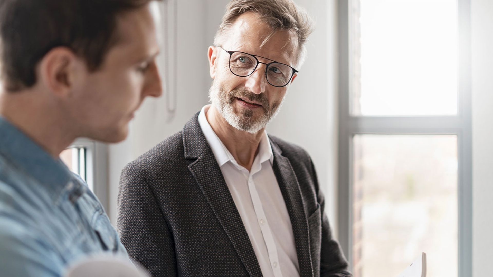 Twee mannen in een kantoor bespreken de resultaten van de EOS Group's European Payment Practices 2025 studie over digitalisering in debiteurenbeheer.