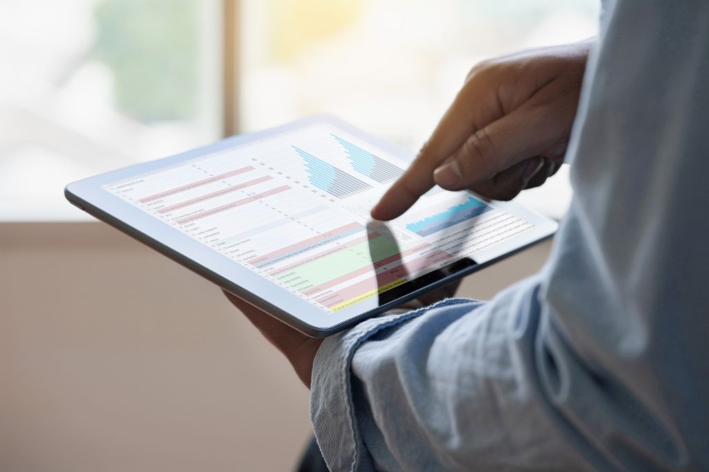 Close up of a man going through a data analysis on a tablet