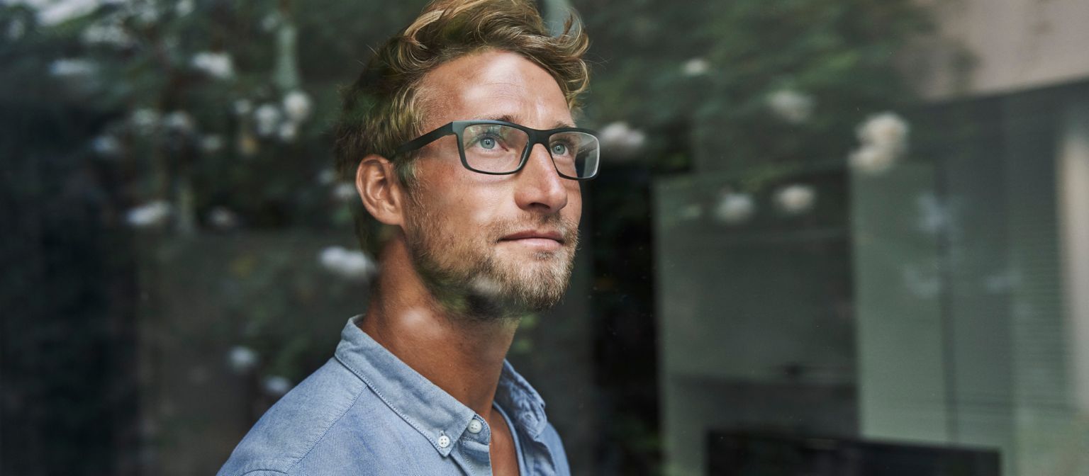 Un jeune homme de la génération Z regarde anxieusement par la fenêtre.