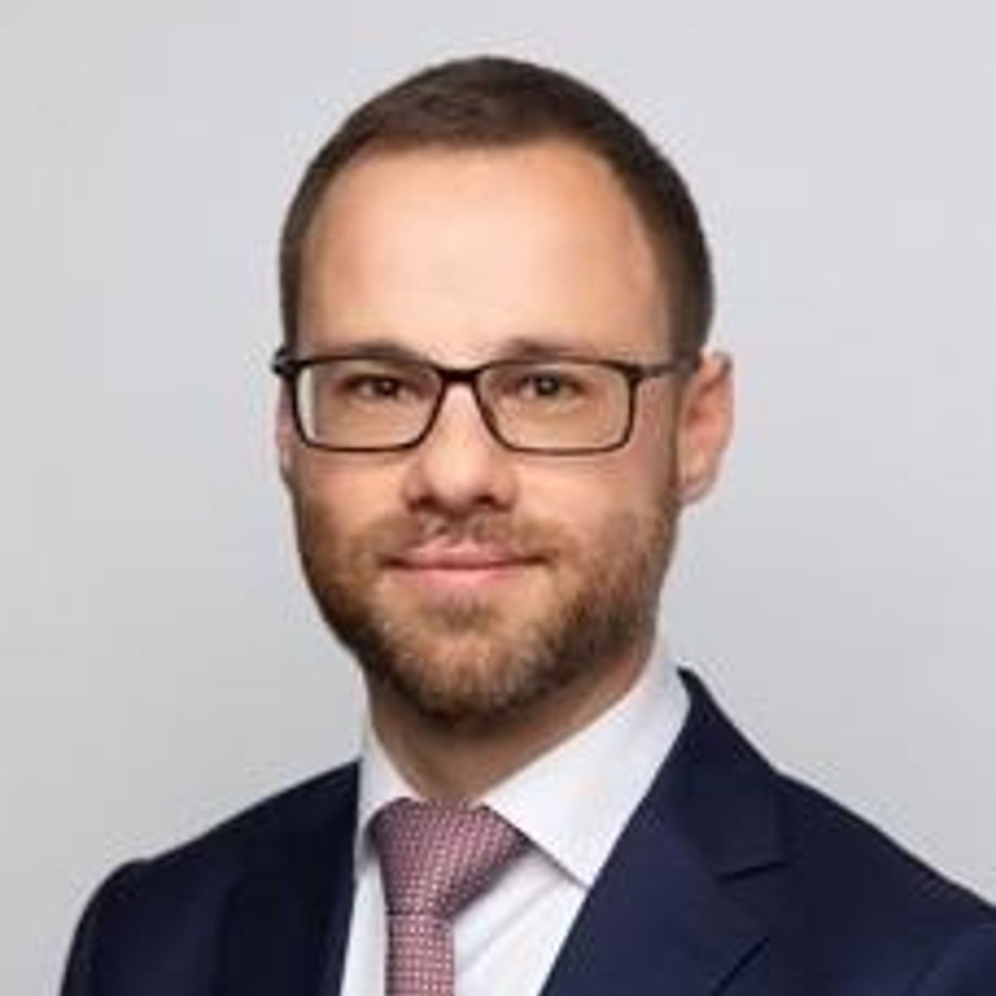 Portret van Nicolas Schneider in pak, naar de camera kijkend.