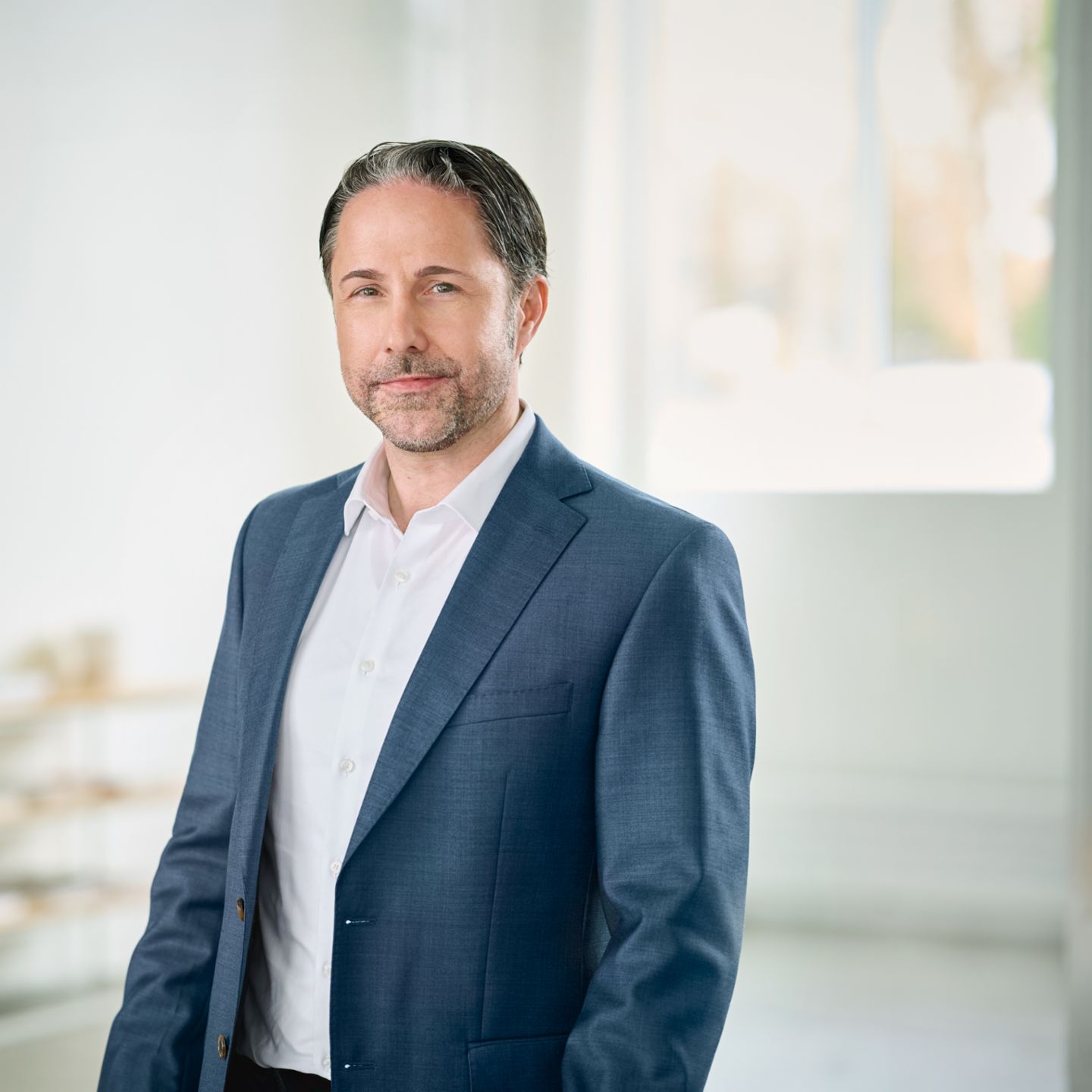 Portret van Marwin Ramcke, voorzitter van de Raad van Bestuur van de EOS-groep, die in een heldere ruimte zit en een donkere blazer draagt. 