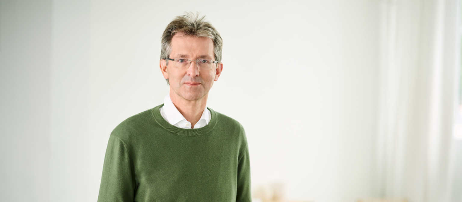 Justus Hecking-Veltman, CFO, staat met een woudgroene trui en wit hemd in een lichte ruimte.