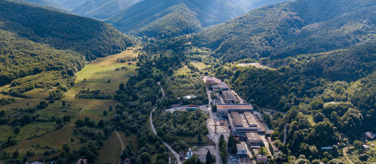 Vorderingenbeheer: Het beeld toont een luchtfoto van de marmerfabriek in Berkovitsa, omringd door veel bomen in een vallei. Dankzij de inzet van EOS is het traditionele bedrijf behouden gebleven.