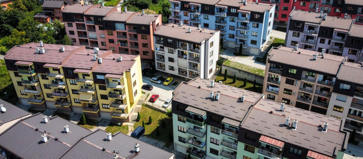 Vastgoed-gedekte vorderingen – luchtfoto van een kleurrijk wooncomplex met meerdere appartementsgebouwen, omgeven door groene zones in Bosnië