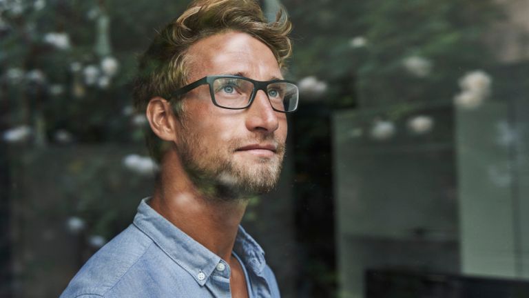 Een jonge man uit Generatie Z kijkt angstig uit het raam.