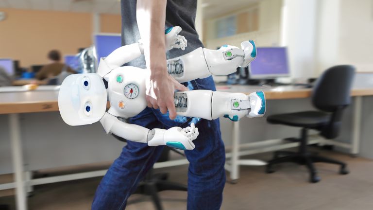 AI in customer service: Staff member carries a robot through the office
