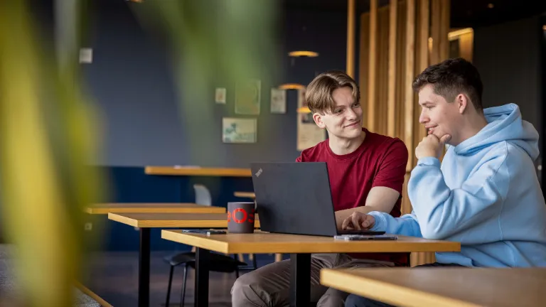 Twee medewerkers werken samen op een laptop en bevorderen partnerschap en eerlijkheid op de werkplek.